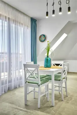 a white dining room with a table and two chairs at MAESTRA Bamboo Beach Luxury Apartment - FREE Parking in Sozopol