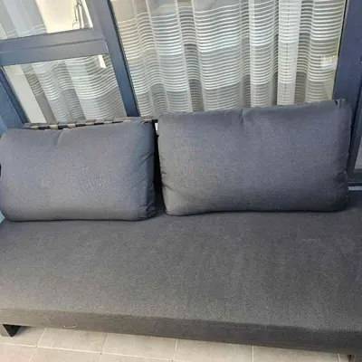 two pillows sitting on a couch in front of a window at Арена Изгрев in Burgas City