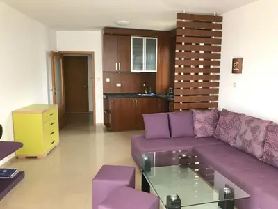 a living room with a purple couch and a kitchen at Apartment Slantse in Sozopol