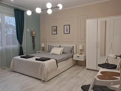 a white bedroom with a bed and a chair at Varna Moreto in Varna City