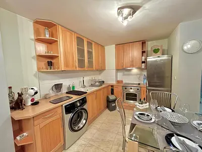 a kitchen with wooden cabinets and a table with chairs at Black Sea Varna Centre in Varna City