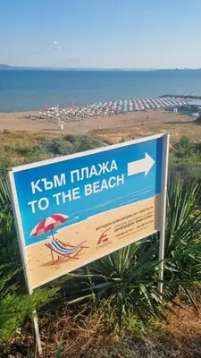 a sign at the beach with the beach in the background at АМИРА апартамент за гости - AMIRA guest apartment in Burgas City