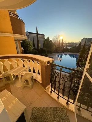a balcony with a table and chairs and a pool at Апартамент с одной спальней in Sunny Beach