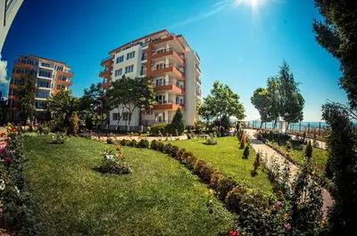 a park with flowers in front of a building at Riviera Fort Beach Apartment in Ravda