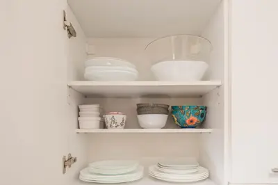 a cupboard filled with plates and bowls and dishes at Varna Beach Apartment in Varna City