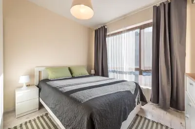 a white bedroom with a bed and a window at Varna Beach Apartment in Varna City