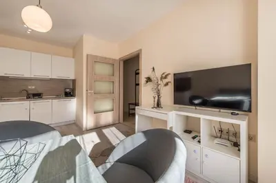 a kitchen with white cabinets and a flat screen tv at Varna Beach Apartment in Varna City