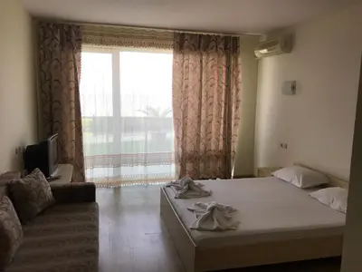 a bedroom with a bed and a couch and a window at Lozenetz Beach Apartments in Lozenets