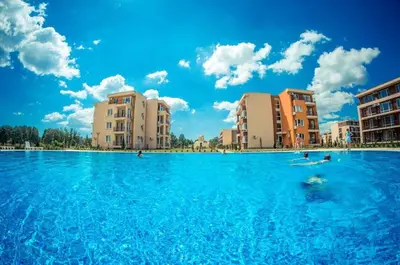 a pool of blue water with buildings in the background at Holiday Fort Golf Club & Orchid Fort Noks MIA in Sunny Beach