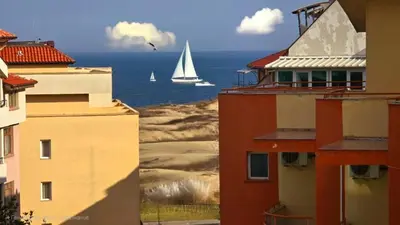 a sailboat in the ocean between buildings with a sail boat at Апартамент Del View гр Приморско in Primorsko