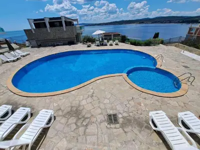 a large blue swimming pool with chairs and water at Panorama Bay-Serenity Haven in Burgas City