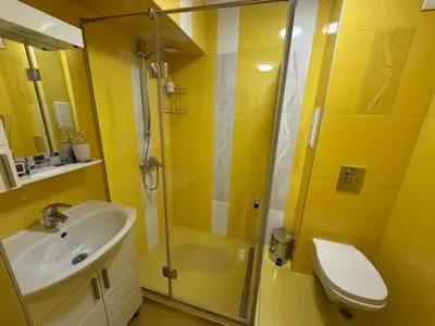 a yellow bathroom with a sink and a shower at Two-Bedroom Apartment in the Heart of Burgas, Bogoridi Street in Burgas City