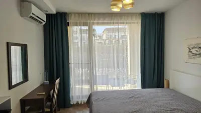 a bedroom with a bed and a desk and a window at Vladan apartments in Sozopol