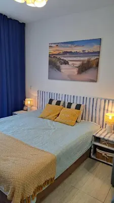 a bedroom with a bed with blue sheets and a painting on the wall at Vladan apartments in Sozopol