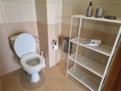 a bathroom with a toilet and shelves in it at SunBreeze Living Apartments in Byala