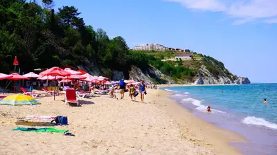 a group of people on a beach with umbrellas and the ocean at Бяла Виста Бийч Апартментс A - Byala Vista Beach Apartments A in Byala