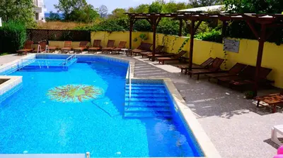 a large swimming pool with chairs and a umbrella at Бяла Виста Бийч Апартментс A - Byala Vista Beach Apartments A in Byala