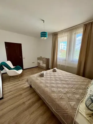 a bedroom with a bed and a chair and a window at Rose Villa in Trŭstikovo