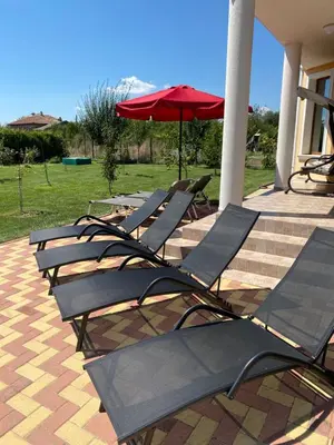 a row of lounge chairs with an umbrella at Rose Villa in Trŭstikovo