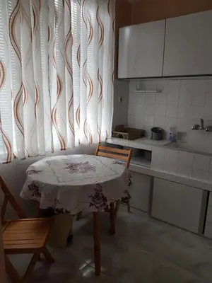 a kitchen with a table and a window with a curtain at Megi Apartments in Sozopol