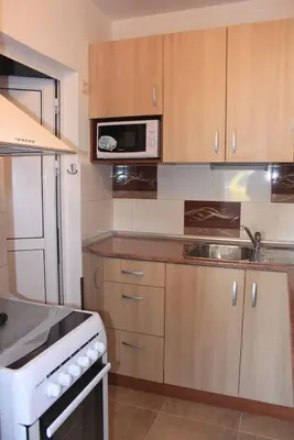 a kitchen with wooden cabinets and a white microwave at Megi Apartments in Sozopol