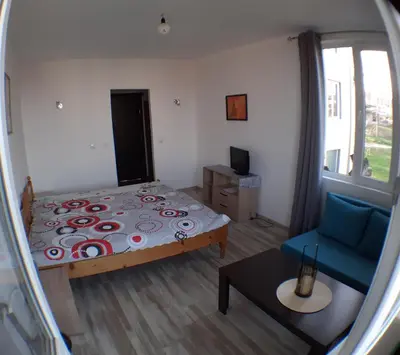a small bedroom with a bed and a blue chair at Sunshine Byala in Byala