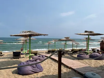 a beach with chairs and umbrellas and the ocean at Sunshine in Byala