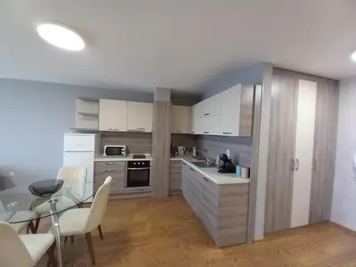 a kitchen with white cabinets and a glass table at Sunset in Chernomorets