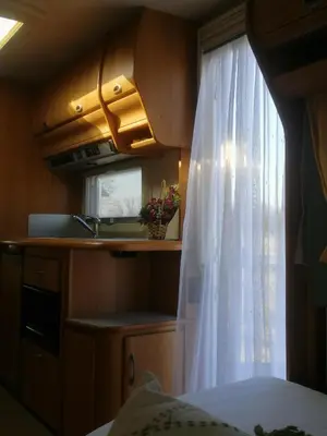 a bedroom with a window with a white curtain at Каравана Сий-я-на in Sozopol