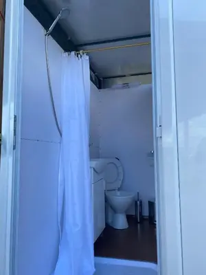 a bathroom with a toilet and a white shower curtain at Каравана Сий-я-на in Sozopol