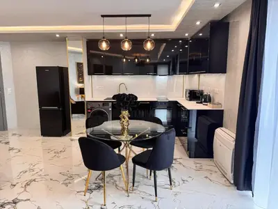 a kitchen with a table and some chairs and a counter at Luxury Apartment with Parking Just Steps from the Beach in the Heart of Burgas! in Burgas City