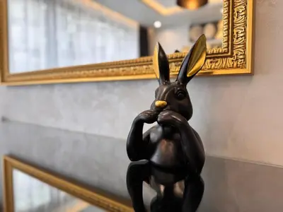 a statue of a rabbit holding a child in front of a mirror at Luxury Apartment with Parking Just Steps from the Beach in the Heart of Burgas! in Burgas City