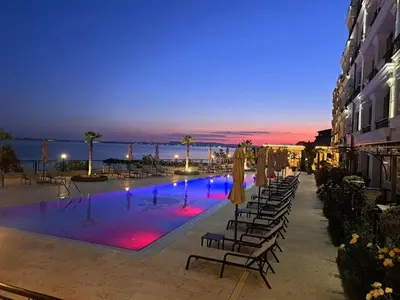 a swimming pool with chairs and umbrellas at night at Onyx Private Apartments in Sveti Vlas