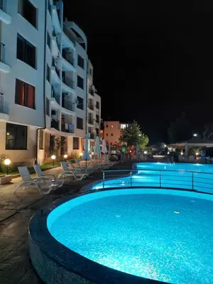 a swimming pool with chairs and a building at night at Avalon Lux in Sunny Beach