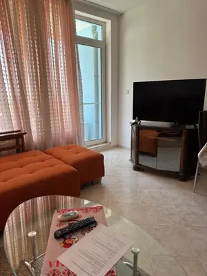 a living room with a couch and a flat screen tv at Apartament Sunset Kosharitsa - Slunchev briag in Kosharitsa