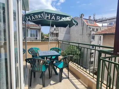 a table and chairs on a balcony with an umbrella at Sunny View Apartment with Garage in Burgas City