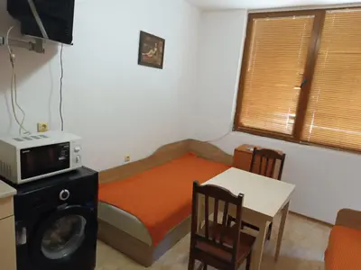 a small room with a bed with a microwave and a table at Stamopolu apartament 1 in Primorsko
