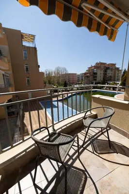 two chairs and an umbrella on a balcony with a pool at Reina Apart Kamelia Garden in Sunny Beach