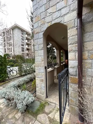 a stone building with a black gate in a yard at Cascadas Family Resort in Sunny Beach