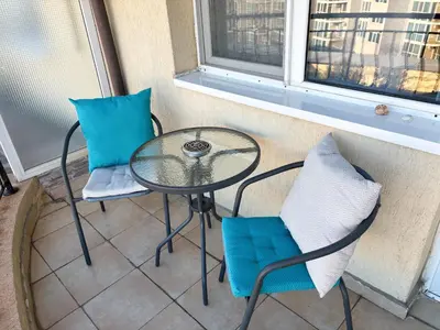 a glass table and two chairs on a balcony at Sea Sunrise Apartment in Burgas City