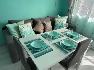 a white table with plates and wine glasses on it at Sea Sunrise Apartment in Burgas City