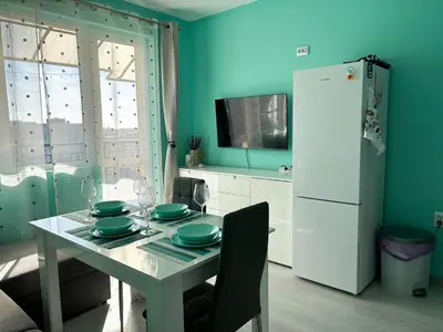 a kitchen with a table and a white refrigerator at Sea Sunrise Apartment in Burgas City