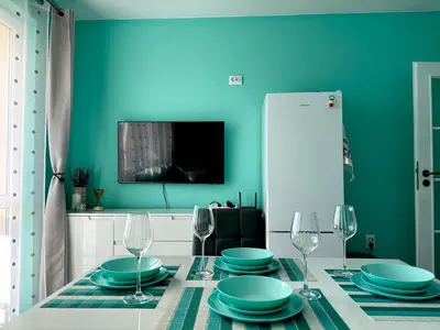 a dining room with a table with plates and wine glasses at Sea Sunrise Apartment in Burgas City