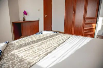 a bedroom with a white bed with a wooden cabinet at Nessebar's NEW Town TOP Centre 2-BDR Apartment by Flаt Manаger in Nesebar