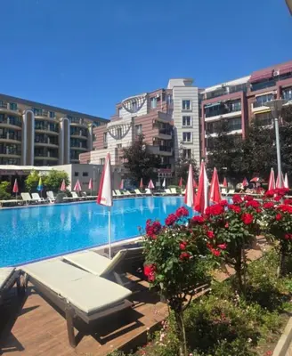 a swimming pool with red and white umbrellas and flowers at Студия в Болгарии Солнечный берег in Sunny Beach