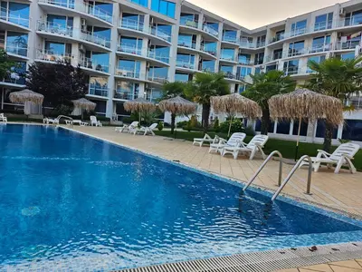 a swimming pool in front of a large apartment building at Студио за гости на Сарафово in Burgas City