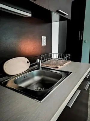 a kitchen sink with a wooden plate next to it at Boho Studio 4 pools 10min to the beach in Burgas City