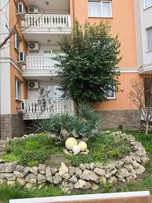 a garden in front of a building with a tree at Sea Diamond Family Suite in Sunny Beach