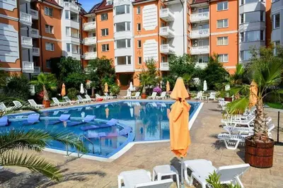 a pool with chairs and an umbrella next to a building at Sea Diamond Family Suite in Sunny Beach