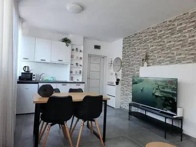 a kitchen and dining room with a table and a tv at Apart VILLA ITTA Sunny Beach in Sunny Beach